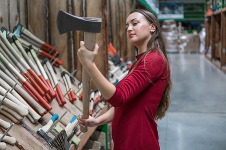 Beautiful young woman holding an wooden handled axe
