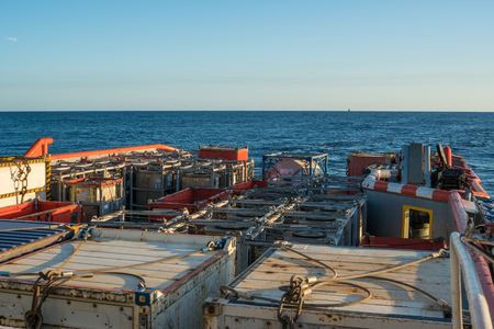 offshore supply boat delivers cargo to oil rig platformの写真素材