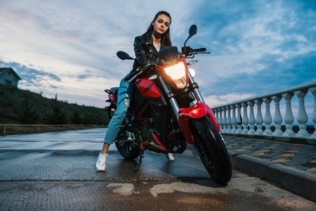 Biker girl in a leather jacket on a black and red color motorcycleの写真素材