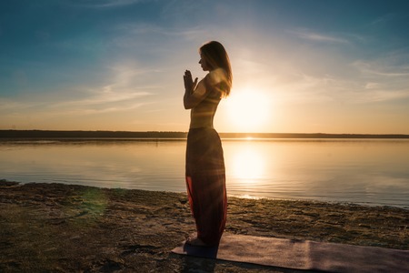 Silhouette yoga woman on the beach at sunset.の写真素材