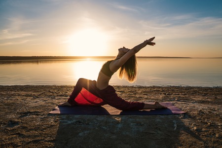 Silhouette yoga woman on the beach at sunset.の写真素材