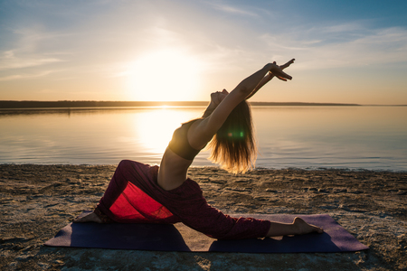 Silhouette yoga woman on the beach at sunset.の写真素材