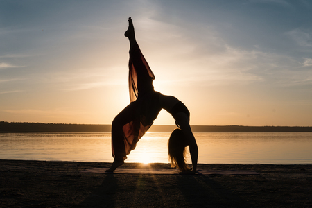 Silhouette yoga woman on the beach at sunset.の写真素材