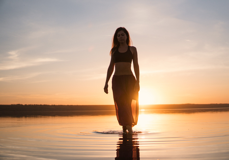 Silhouette yoga woman on the beach at sunset.の写真素材
