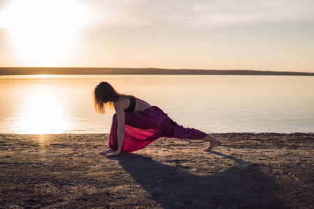 Silhouette yoga woman on the beach at sunset.の写真素材