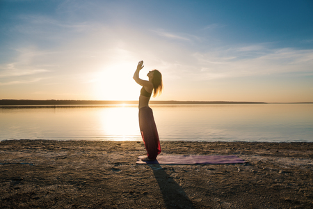 Silhouette yoga woman on the beach at sunset.の写真素材