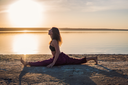 Silhouette yoga woman on the beach at sunset.の写真素材
