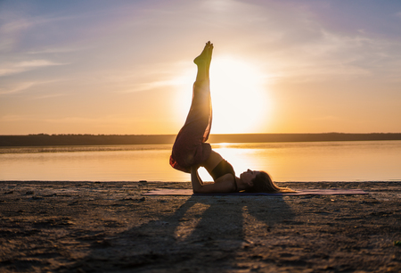 Silhouette yoga woman on the beach at sunset.の写真素材