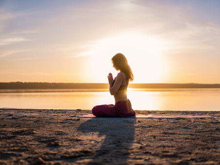 Silhouette yoga woman on the beach at sunset.の写真素材