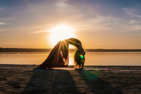 Silhouette yoga woman on the beach at sunset.の写真素材