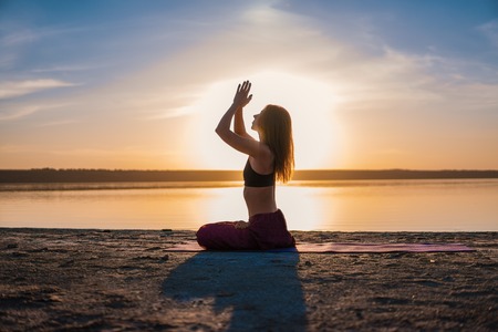 Silhouette yoga woman on the beach at sunset.の写真素材