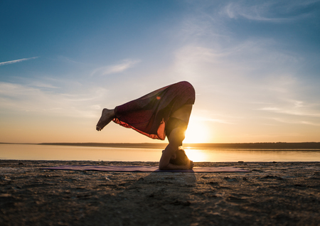 Silhouette yoga woman on the beach at sunset.の写真素材