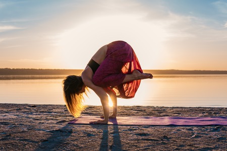 Silhouette yoga woman on the beach at sunset.の写真素材