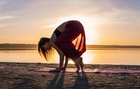 Silhouette yoga woman on the beach at sunset.の写真素材