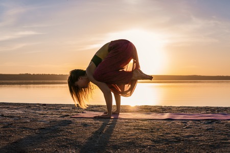 Silhouette yoga woman on the beach at sunset.の写真素材