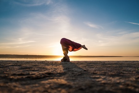 Silhouette yoga woman on the beach at sunset.の写真素材