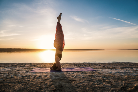 Silhouette yoga woman on the beach at sunset.の写真素材