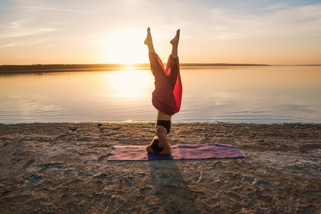 Silhouette yoga woman on the beach at sunset.の写真素材