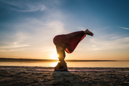 Silhouette yoga woman on the beach at sunset.の写真素材