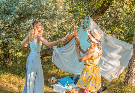 Playful girls fighting with bread baguette making picnicの写真素材