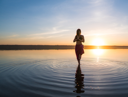 Silhouette yoga woman on the beach at sunset.の写真素材
