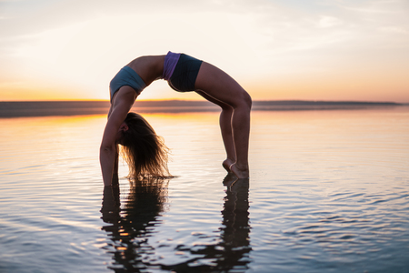 yoga woman on the beach at sunset.の写真素材