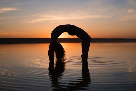 Silhouette yoga woman on the beach at sunset.の写真素材