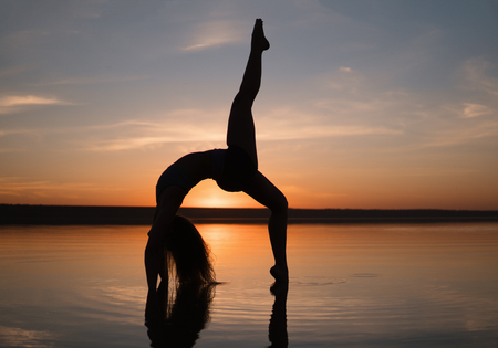 Silhouette yoga woman on the beach at sunset.の写真素材