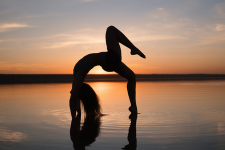Silhouette yoga woman on the beach at sunset.の写真素材