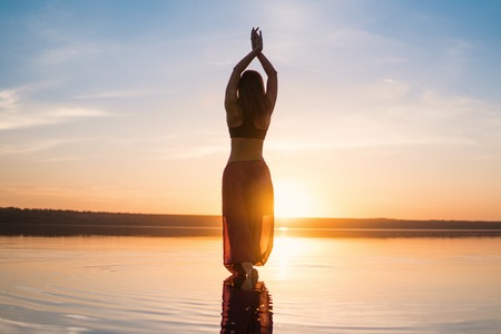 Silhouette yoga woman on the beach at sunset.の写真素材