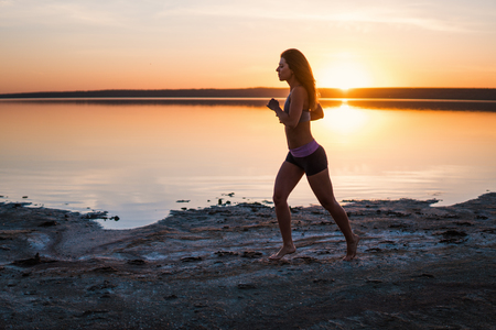 Woman Running on the Beach at Sunsetの写真素材
