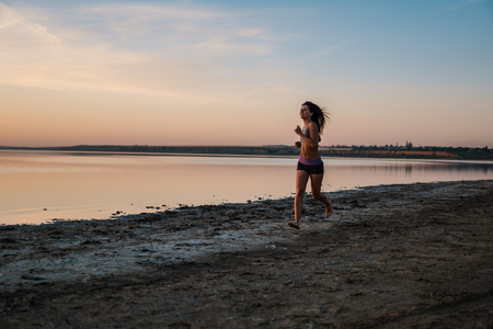 Woman Running on the Beach at Sunsetの写真素材