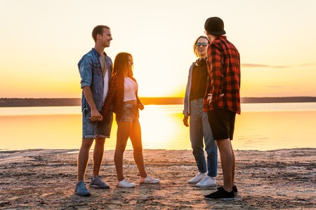 couple friends on beach together walking during sunsetの写真素材