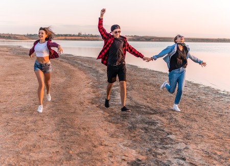 young hipster friends on beach running togetherの写真素材