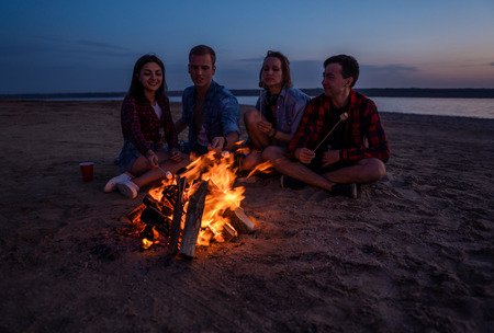 young friends have picnic with bonfire on the beachの写真素材