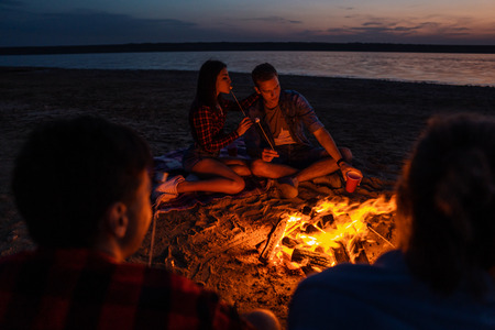young friends have picnic with bonfire on the beachの写真素材