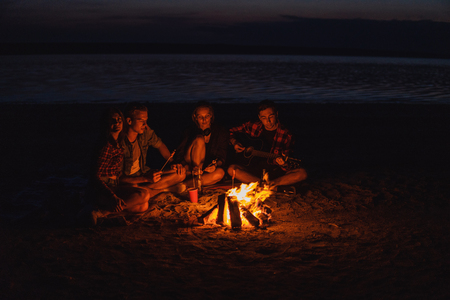 young friends have picnic with bonfire on the beachの写真素材