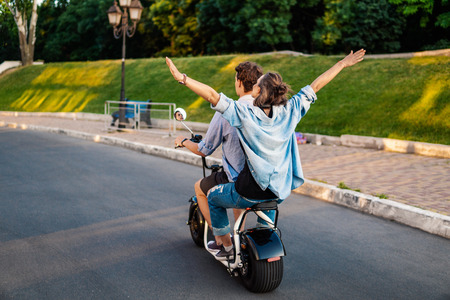 Lovely young couple driving electric bike during summerの写真素材