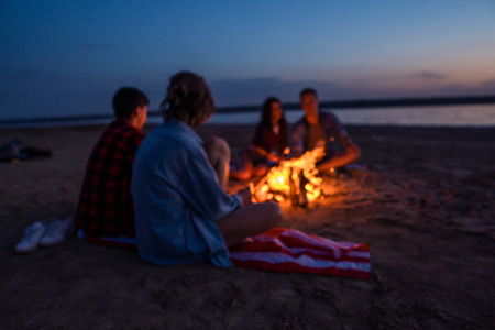 young friends have picnic with bonfire on the beachの写真素材