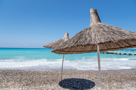tropical umbrellas on a island beach. Blue ocean on backgroundの写真素材