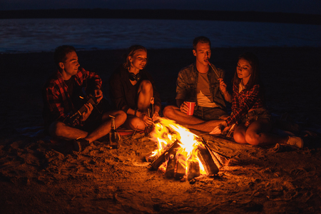 young friends have picnic with bonfire on the beachの写真素材