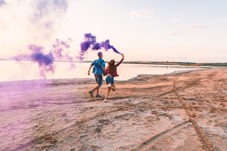 young couple running with hand flare or fuseeの写真素材