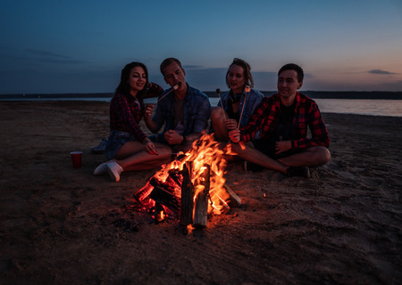 young friends have picnic with bonfire on the beachの写真素材