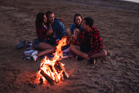 young friends have picnic with bonfire on the beachの写真素材