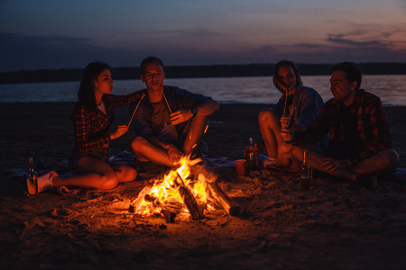 young friends have picnic with bonfire on the beachの写真素材