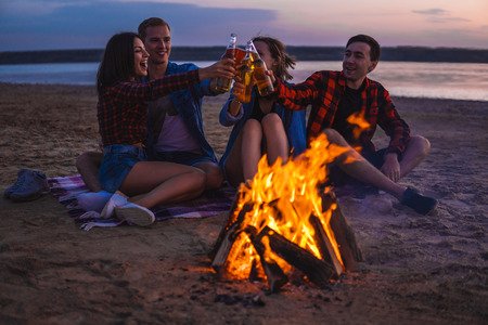 young friends have picnic with bonfire on the beachの写真素材