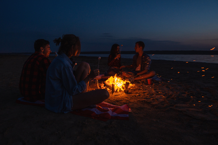 young friends have picnic with bonfire on the beachの写真素材