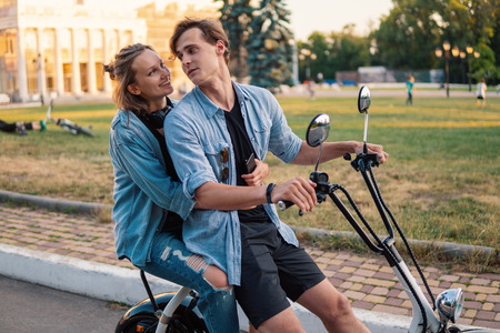 Lovely young couple driving electric bike during summerの写真素材