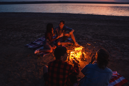 young friends have picnic with bonfire on the beachの写真素材