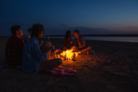 young friends have picnic with bonfire on the beachの写真素材